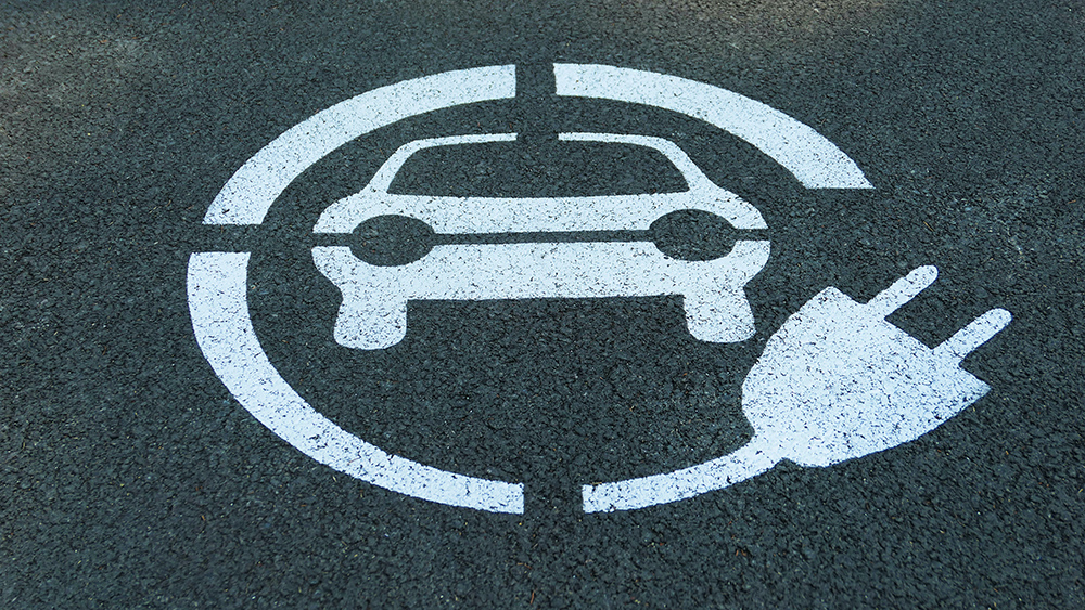 A painted symbol on asphalt used to show where electric cars can charge - an icon car surrounded by a broken circle with a plug at one end.